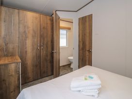 A bedroom with a wardrobe and towels on the bed at Woodlands Gold (WO40) in Ruthin