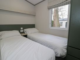 A bedroom with two single beds and a window at Woodlands Gold (WO06) in Ruthin