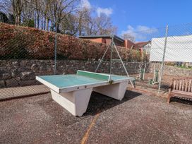 An outdoor area with a table tennis table and a bench at Woodlands Gold in Ruthin