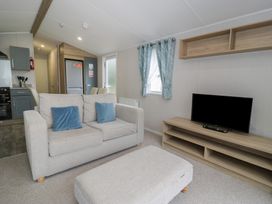A living room with a sofa, television, and window at Woodlands Platinum (WO29) Ruthin