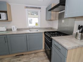 A kitchen featuring cabinets, a sink, stove, and utensils at Woodlands Platinum (WO29) in Ruthin