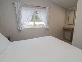 A bedroom with a bed, window, and table at Woodlands Platinum in Ruthin