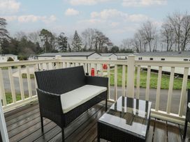 An outdoor seating area with a chair and table at Woodlands Platinum in Ruthin