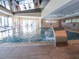 An indoor swimming pool with a fountain and lounge chairs at Woodlands Platinum (WO29) Ruthin
