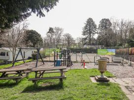 An outdoor recreation area with swings and a basketball court at Woodlands Platinum (WO29) in Ruthin