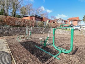 An outdoor exercise area with equipment and a stone wall at Woodlands Platinum (WO29) in Ruthin