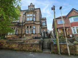 A street view of two adjacent houses one with stone facade and stairs leading to the entrance at Coronation House in Scarborough