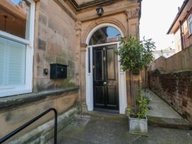 Entrance to a building with a black door numbered six and potted trees at Coronation House in Scarborough