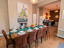 A dining room with a set table and brown chairs next to a kitchen with a white fridge at Coronation House in Scarborough