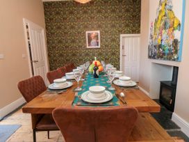 A dining room with a wooden table set for a meal with plates glasses and cutlery at Coronation House in Scarborough