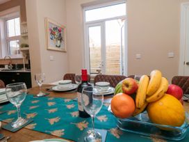 A dining table set with wine glasses bowls plates a bottle of wine and a bowl of fruit in a room with glass doors at Coronation House in Scarborough