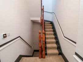 A carpeted staircase with wooden banisters and white walls with black trim at Coronation House in Scarborough