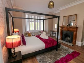 A bedroom with a four-poster bed beside a fireplace and a window seating area at Coronation House in Scarborough