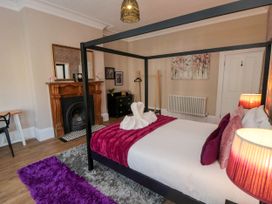 A bedroom with a four-poster bed a fireplace and a purple rug at Coronation House in Scarborough