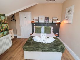 A bedroom with a double bed green cushions towel swans pictures on headboard at Coronation House in Scarborough