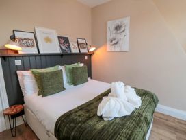 A bedroom with a bed with green cushions and a green throw with towel art on it at Coronation House in Scarborough