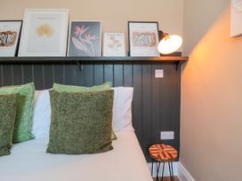 A bed with green cushions next to a side table and framed pictures on a shelf at Coronation House in Scarborough
