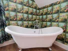 A bathroom with a white clawfoot bathtub and floral wallpaper at Coronation House in Scarborough