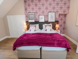 A bedroom with two single beds pushed together with pink bedding and decorative pillows at Coronation House in Scarborough