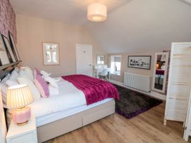 A bedroom with a bed a desk chair lamp and a standing mirror at Coronation House in Scarborough