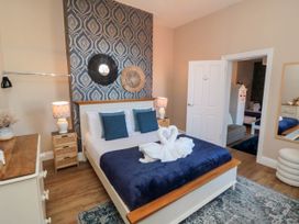 A bedroom with a bed with blue pillows and blanket a dresser and lamps at Coronation House Scarborough