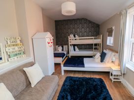 A bedroom with bunk beds a single bed a sofa a wardrobe and a bedside table with a lamp at Coronation House in Scarborough