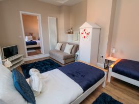A bedroom with two single beds a small sofa a television and a wardrobe at Coronation House in Scarborough