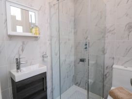 A bathroom with a shower enclosure a toilet a sink with a cabinet and a wall mirror at Coronation House in Scarborough