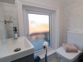 A small bathroom with a sink soap dispenser toilet with folded towel and frosted window at Coronation House in Scarborough
