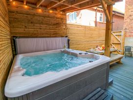 An outdoor covered patio with a hot tub wooden fence and a table set with food and wine at Coronation House in Scarborough