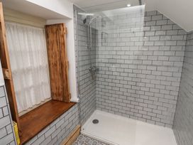 A bathroom shower area with tiled walls a glass shower screen and a wooden framed window at The Old Coach House Eglingham near Alnwick
