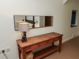 A wooden table with a lamp and a mirror above it in a hallway at The Old Coach House in Eglingham near Alnwick