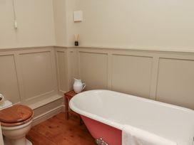 A bathroom with a freestanding bathtub a wooden toilet seat and a small wooden side table at The Old Coach House in Eglingham near Alnwick