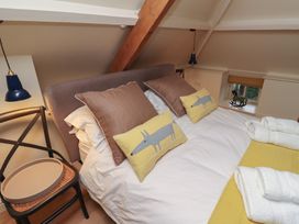 A bedroom with a bed pillows and rolled towels next to a wooden chair and small window at The Old Coach House in Eglingham near Alnwick