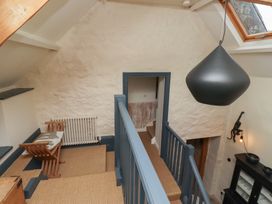 A stairway landing with a wooden chair and a radiator near a doorway and a black hanging light at The Old Coach House in Eglingham near Alnwick