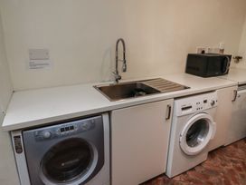 A utility room with a washing machine dryer sink and microwave at The Old Coach House in Eglingham near Alnwick