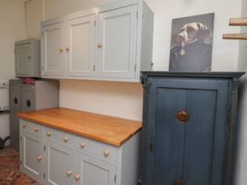 A room with grey cabinets and a wooden countertop a blue cabinet and a painting of a dog in formal clothing at The Old Coach House Eglingham near Alnwick
