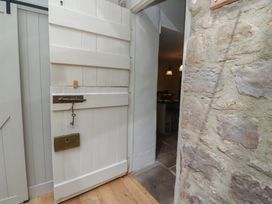 A partially open white wooden door with a key in the lock next to a stone wall at The Old Coach House in Eglingham near Alnwick