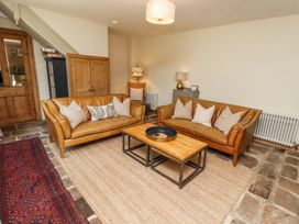 A sitting room with two brown leather sofas a wooden coffee table and a woven rug at The Old Coach House in Eglingham near Alnwick