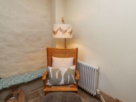 A wooden chair with cushions next to a radiator and a floor lamp with bird patterns in a corner