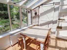 A dining area with a wooden table, chairs, large windows showing a garden, and a sliding barn door at The Old Coach House in Eglingham near Alnwick