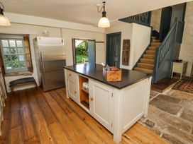 A kitchen with a central island, stainless steel refrigerator, window with seat, and staircase at The Old Coach House in Eglingham near Alnwick