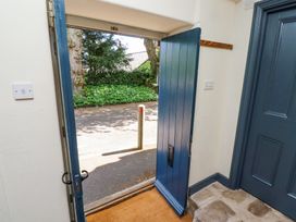 An open blue door showing a view of a driveway with greenery and trees outside at The Old Coach House in Eglingham near Alnwick