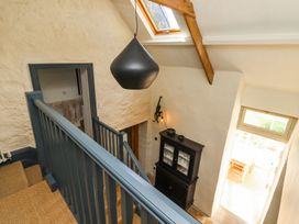 A staircase with blue railing looking down to a black cabinet and a window at The Old Coach House in Eglingham near Alnwick