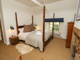 A bedroom with a four poster bed bedside table window and fireplace at The Old Coach House in Eglingham near Alnwick