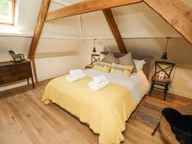 A bedroom with a double bed yellow blanket wooden beams and wooden floor at The Old Coach House in Eglingham near Alnwick