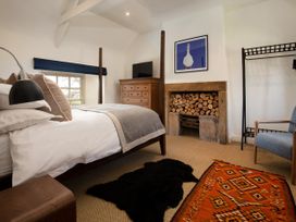 A bedroom with a bed, dresser, chair and fireplace at The Old Coach House in Eglingham near Alnwick