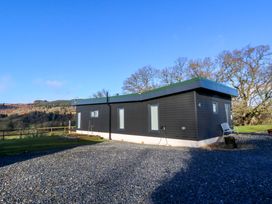 A modern single-story house with dark exterior walls and flat roof on a gravel driveway at Dundarach in Aberfeldy