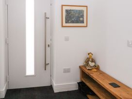 An entryway with a white door a wooden bench with a duck doll and a pair of black boots on a carpet at Dundarach in Aberfeldy