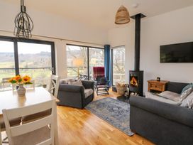 A living room with sofas a wood stove and large windows showing a landscape at Dundarach in Aberfeldy